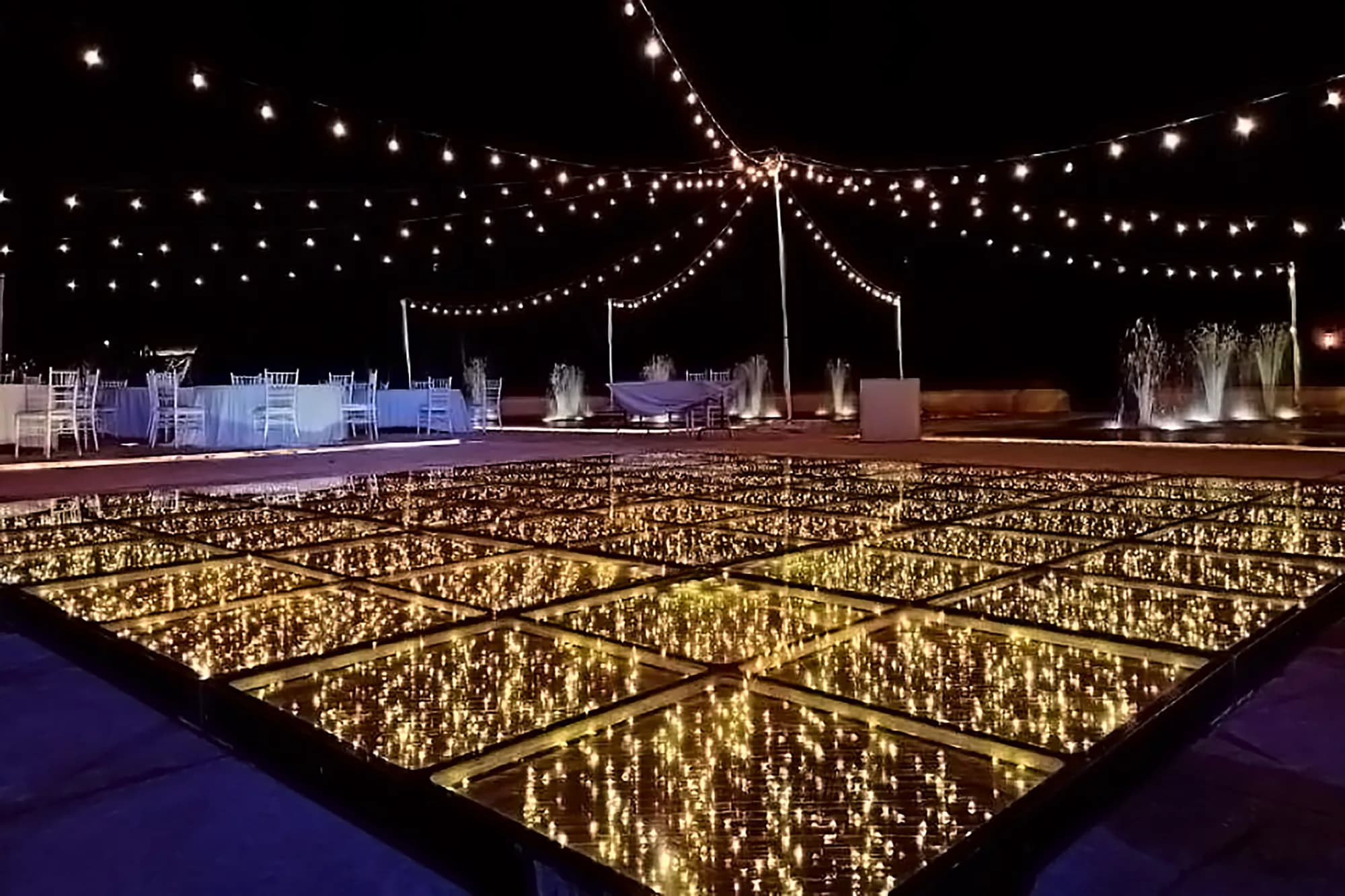 Gold infinity mirror dance floor installed outdoors under string lights at an Orlando wedding
