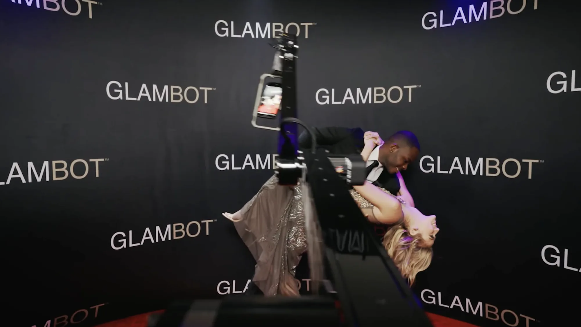 Guests posing for the Glambot camera against a branded step and repeat