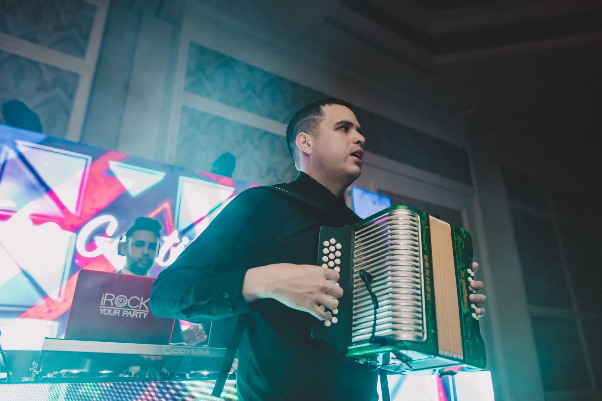 Accordion player performing live alongside the DJ in front of an LED wall at an Orlando event